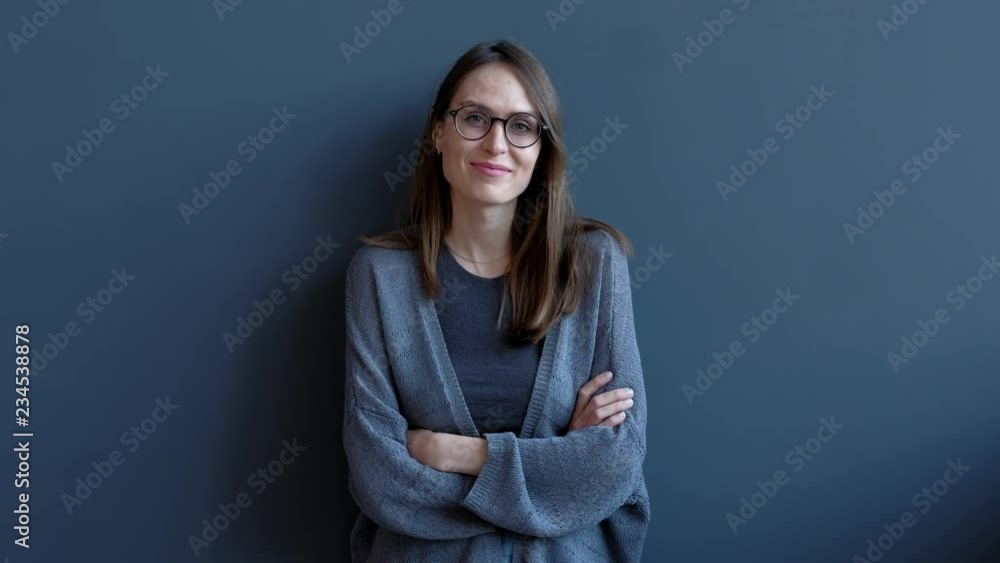 Young Positive woman looking at camera and smiling. Portrait of Cute Female with flowing hair with glasses on black background. Young Positive woman looking at camera and smiling. Portrait of Cute Female with flowing hair with glasses on black background.
