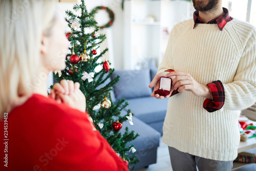 Young man giving cute jewellery to his wife or girlfriend on Christmas day