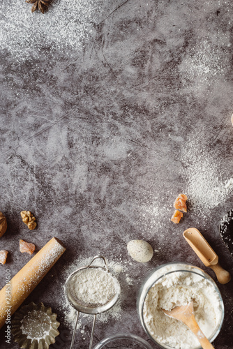 Healthy baking ingredients. Spoon with flour, dishes, eggs, butter salt and rolling pin on a grey background.Bakery background frame. Top view, copy space.