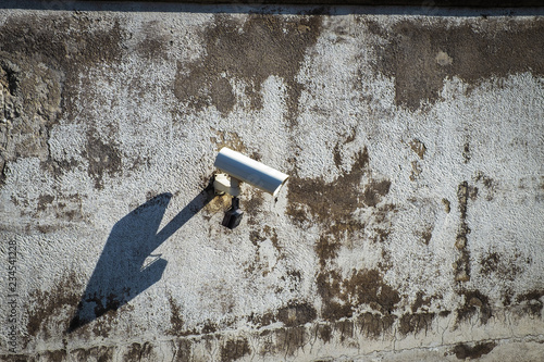 Shadowing, close up of videcam at street on old grung building wall photo