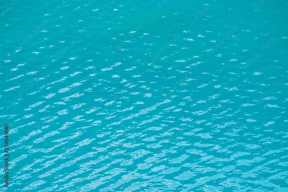 Amazing textured background of calm azure clean water surface. Sunshine in mountain lake close up. Beautiful ripples on shiny water in sunny day. Wonderful relax texture.
