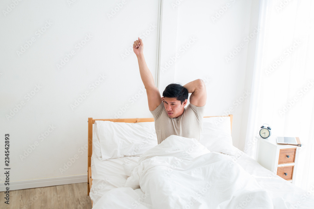 Asian handsome man waking up in the early morning. Outstretched arms. People always stretch after they get up in the morning