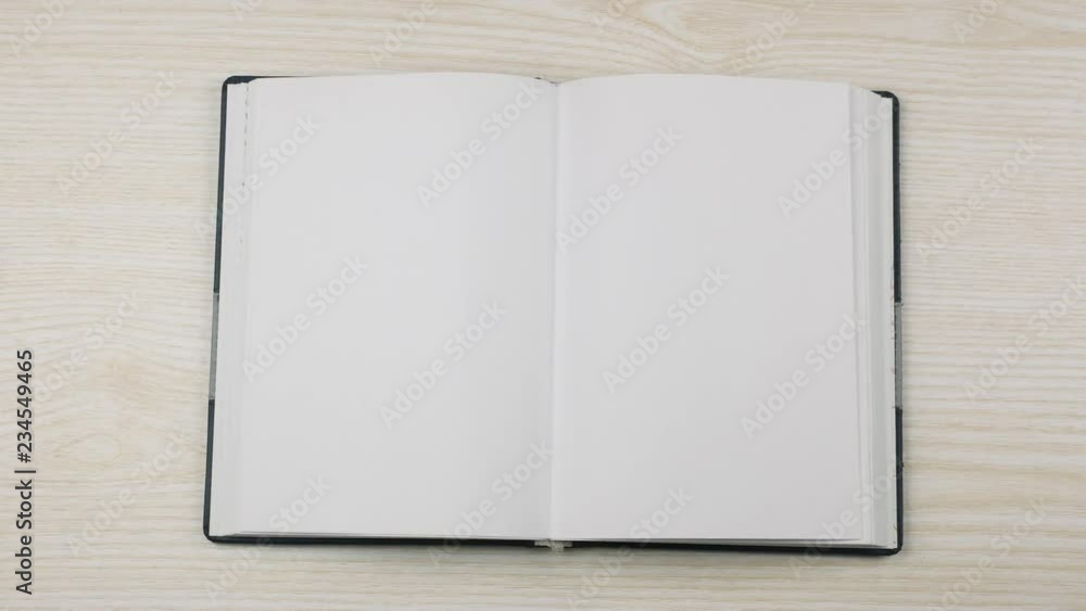 The hand of a businessman puts and opens an empty diary on the table. The hand of a businessman puts and opens an empty diary on the table.