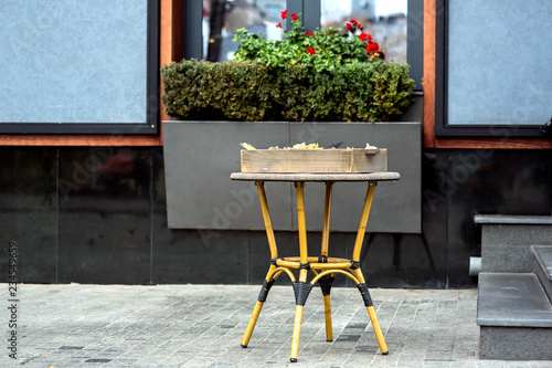 Wicker table with a box of traditional Italian unary facade of a dark-colored restaurant with a flower pot under the window. photo