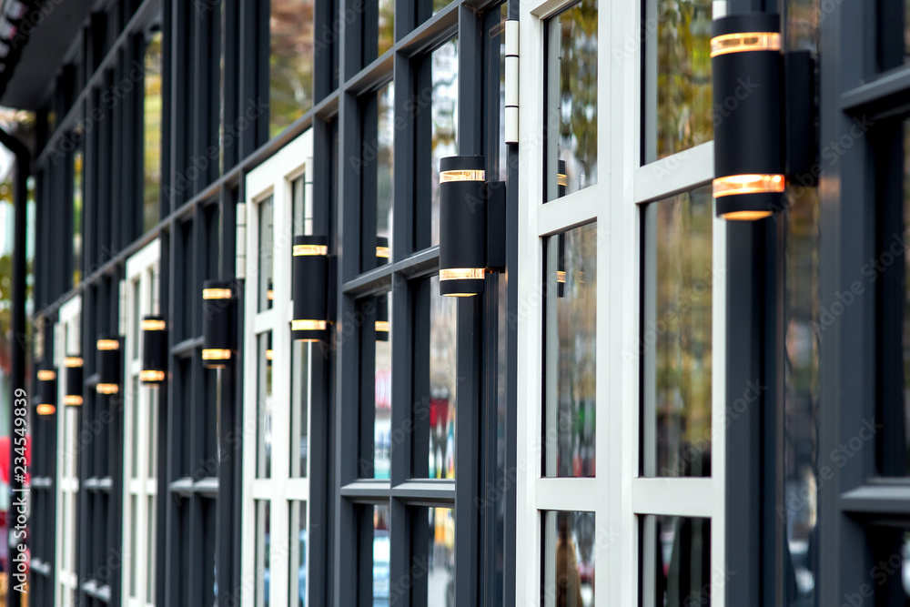 Close-up of a dark facade with white windows and black modern decorative lanterns, the exterior of the restaurant.