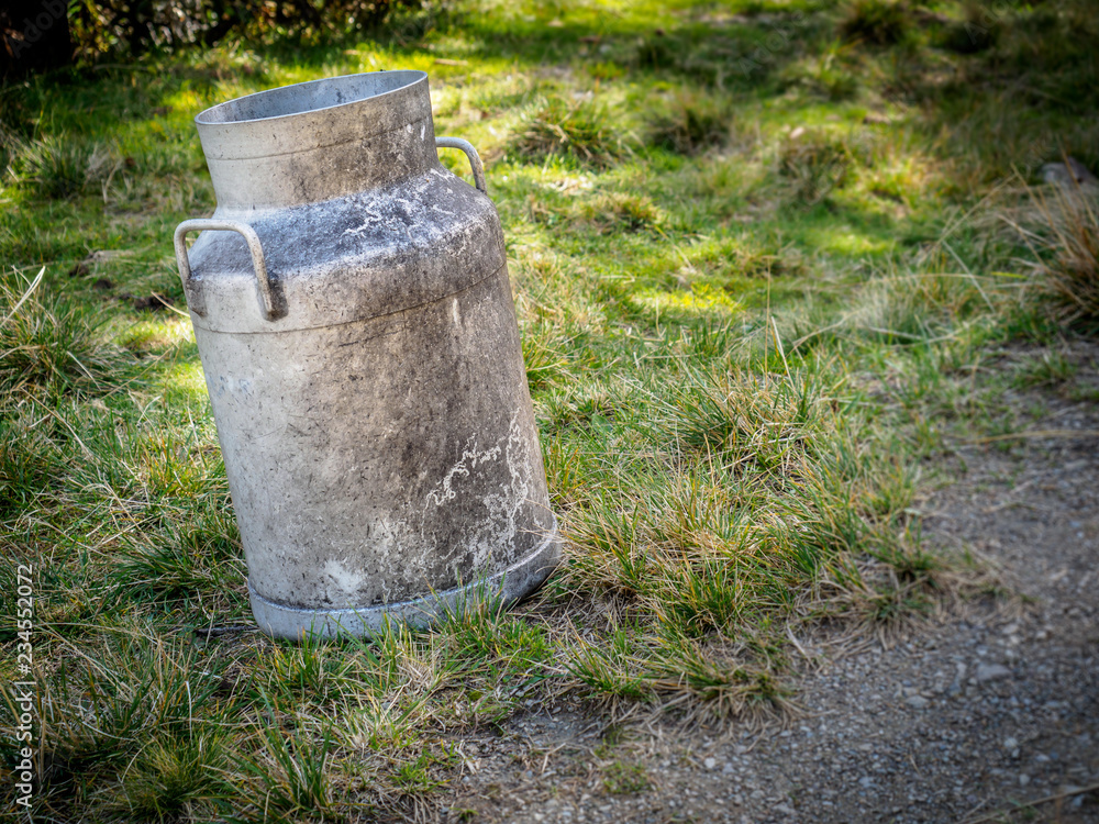 old milk can next to a foot path old milk can next to a foot path