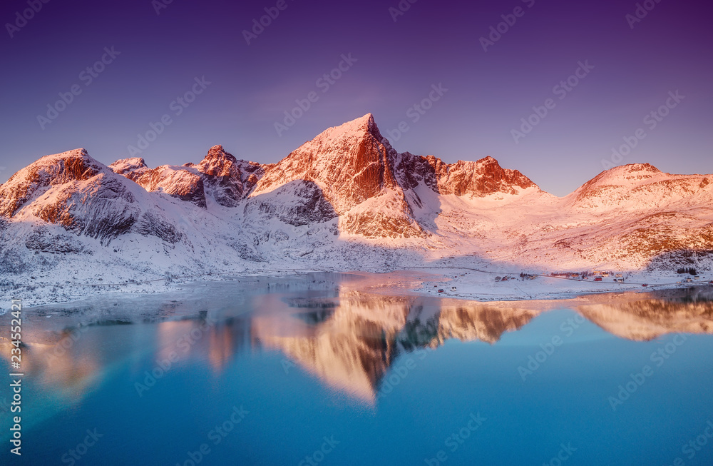 Aerial view at the mountains and reflection on the water surface. Lofoten islands, Norway. Natural landscape during sunrise from air.