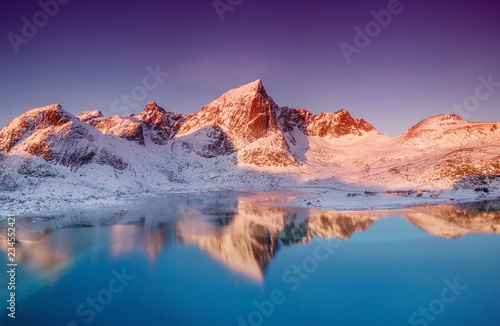 Fototapeta Naklejka Na Ścianę i Meble -  Aerial view at the mountains and reflection on the water surface. Lofoten islands, Norway. Natural landscape during sunrise from air.