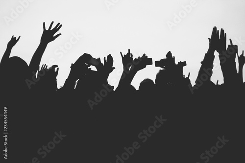 Hands silhouettes of the crowd raised up at music show. Black and white picture