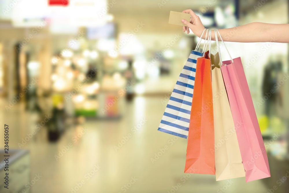 Woman with shopping bags and card on mall background