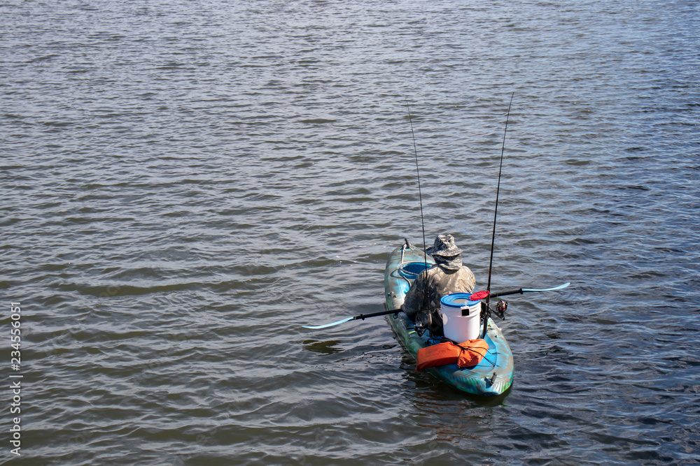 man fishing in a kayak on a peaceful lake