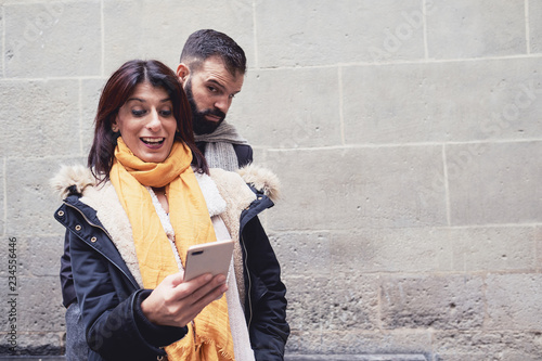 un hombre observa y espía el móvil de una mujer de forma sospechosa