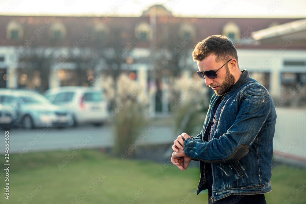 Young impatient man standing and looking at his watch, while waiting for a friend Young impatient man standing and looking at his watch, while waiting for a friend