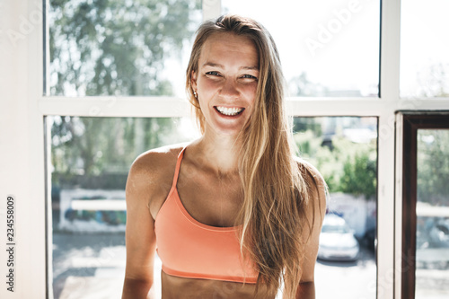 Portrait of sunburn fit woman wearing sportwear in sunny white gym