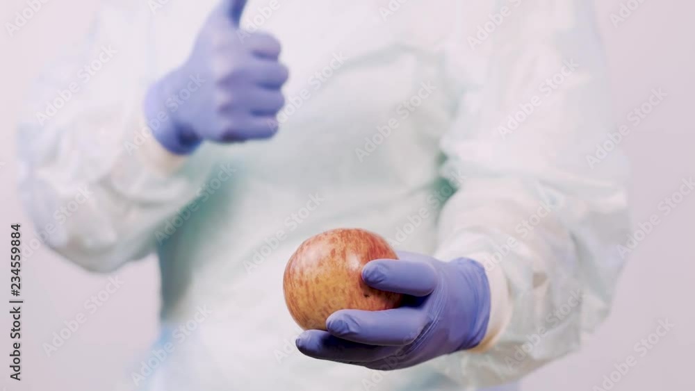 The doctor holds out an apple to the patient. Hands in medical gloves, closeup. The doctor holds out an apple to the patient. Hands in medical gloves, closeup.