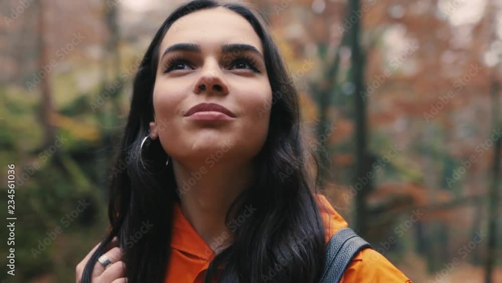 Close up brunette attractive young woman stand smile look around in forest outdoors with yellow leaves foliage autumn backpack hiker vacation portrait slow motion Close up brunette attractive young woman stand smile look around in forest outdoors with yellow leaves foliage autumn backpack hiker vacation portrait slow motion