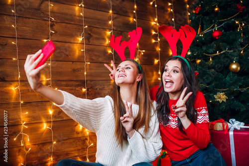 Two best friends taking selfie in bedroom near Christmas tree