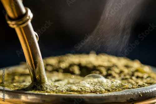 Steaming delicious yerba mate in a traditional calabash gourd, horizontal closeup. photo
