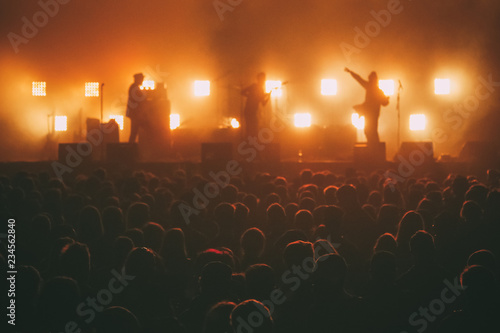  Crowd of big music festival with rock band silhouette on a stage in a backlights at the background