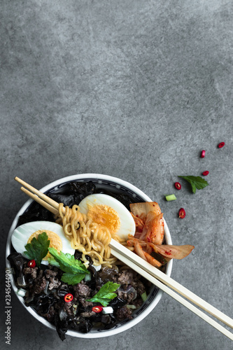 Korean ramen soup with minced meat , egg, asian mushroom and kimchi on a grey neutral background. Flat lay. copy space.