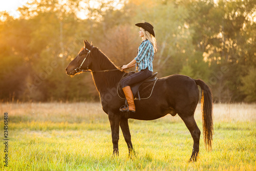 Girl equestrian rider riding a beautiful horse in the rays of the setting sun.