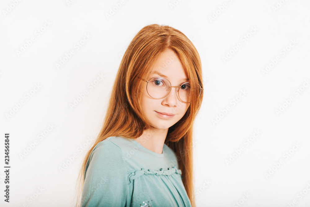 Studio shot of young preteen red-haired girl against white background, wearing eyeglasses Studio shot of young preteen red-haired girl against white background, wearing eyeglasses