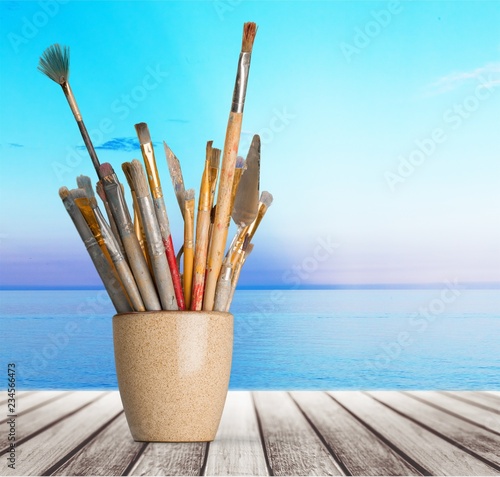 Brushes in a glass jar on the table and white wall