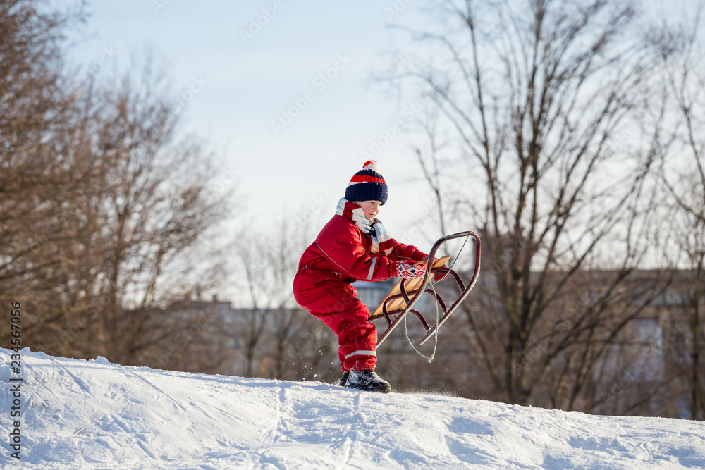 boy at the sledge on the top of snowy hill waiting for riding