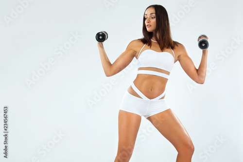 Sporty fit woman, athlete with dumbbells makes fitness exercising on white background.