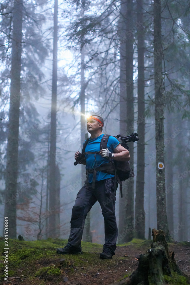 Man with headlamp and backpack in the forest - obrazy, fototapety, plakaty 