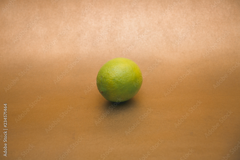 Fresh whole lime isolated on  gold background