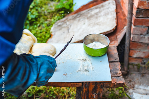 The woman in oversleeves cooks dough for home-made bread on open air photo