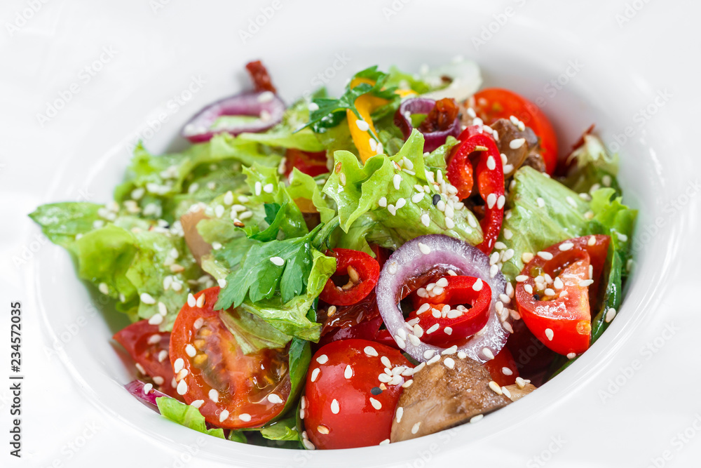 Fresh vegetable salad with lettuce, grilled mushrooms, tomatoes, sweet peppers and sesame seeds on plate on light wooden background close up. Healthy food. Top view Fresh vegetable salad with lettuce, grilled mushrooms, tomatoes, sweet peppers and sesame seeds on plate on light wooden background close up. Healthy food. Top view