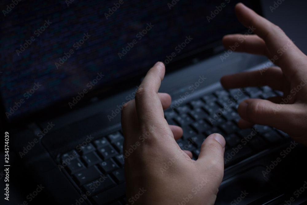 Internet hacker thief concept. Hacker using laptop to attack computer equipment. Dark and scary lighting. A lot of symbols on the computer screen. Selective focus. Internet hacker thief concept. Hacker using laptop to attack computer equipment. Dark and scary lighting. A lot of symbols on the computer screen. Selective focus.