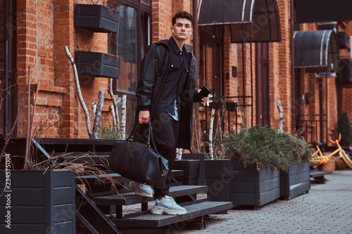 A young fashionable man comes down the stairs outside.