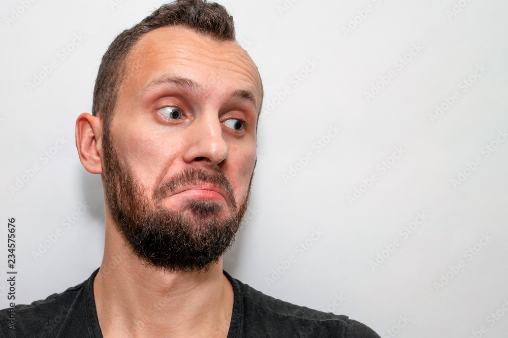 Obraz premium portrait of a young bearded guy with a surprised and astonished face, copyspace