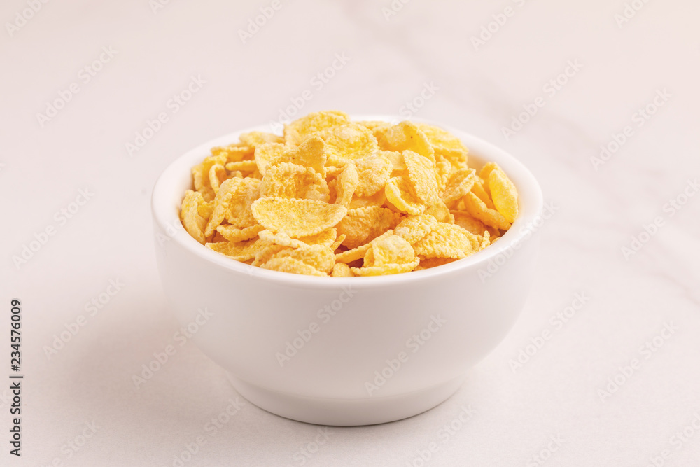 Crispy corn flakes in clay bowl on light marble background Crispy corn flakes in clay bowl on light marble background