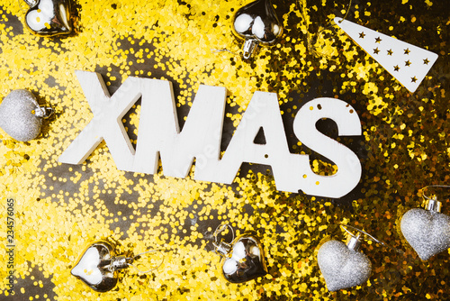 Xmas text decoration on a black board with golden glitter sequin, and decoration, flat lay, top view, concept for holiday and copyspace left.