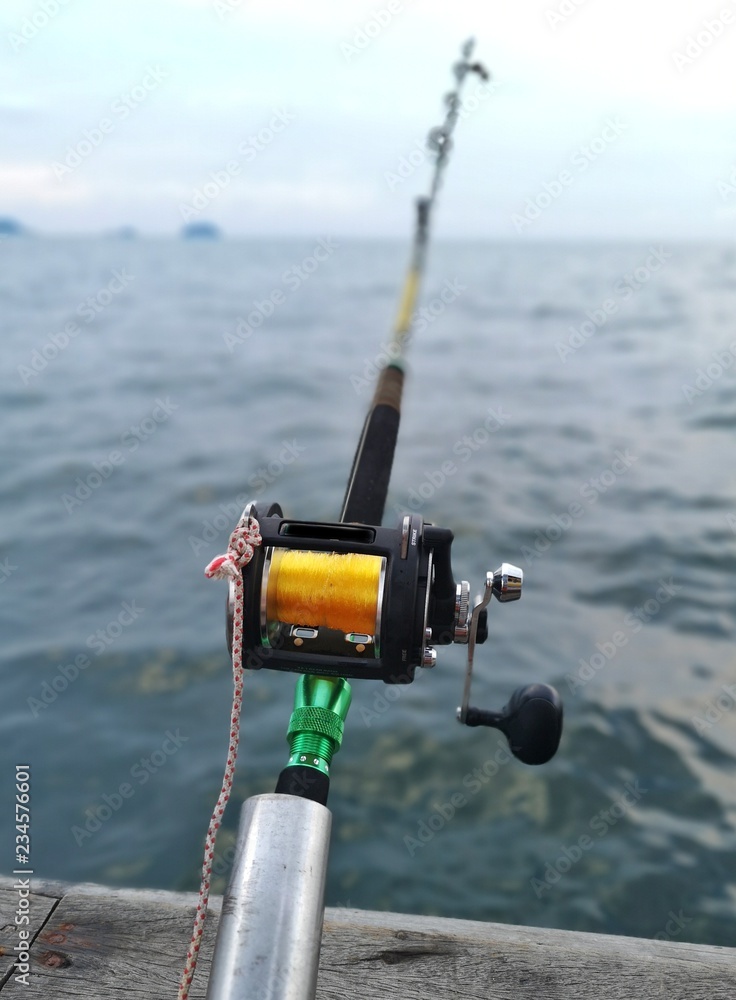 Multiplier fishing reel by the boat on ocean background Multiplier fishing reel by the boat on ocean background