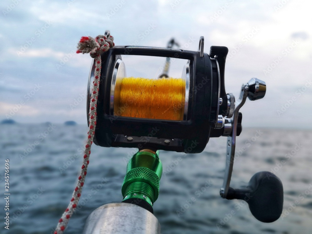 Multiplier fishing reel by the boat on ocean background Stock Photo
