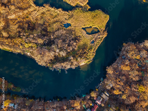 Top view from drone point of view of colorful autumn forest on bank of blue river