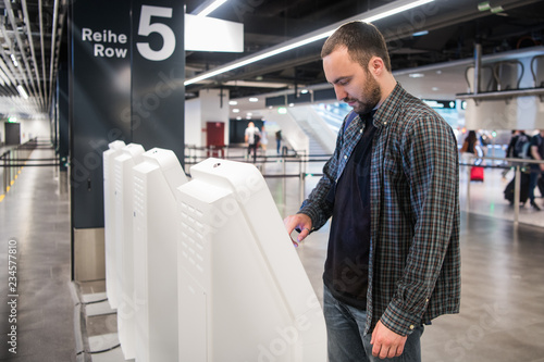 Young man using self check-in kiosks in airport.