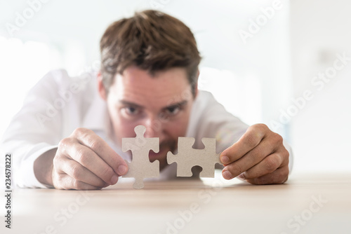 Young businessman joining two matching puzzle pieces photo