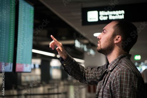 Man is looking at flight arrivals and departures board at airport