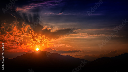sun setting behind silhouetted mounatins © christos