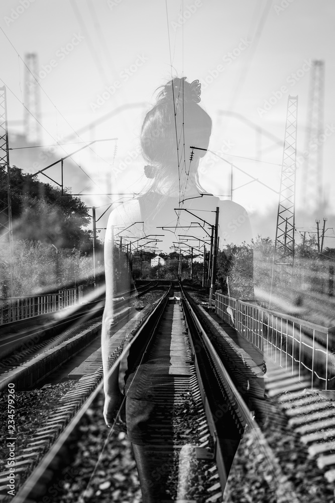 The concept of moving along the railway towards the horizont. Man in a raincoat from the back. Black and white image.