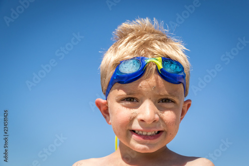 Little Boy Wearing Blue Goggles and Smiling at the Camera © Dallas
