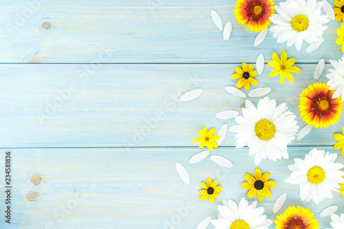 White daisies and garden flowers on a light blue worn wooden table. Empty space on the other side.