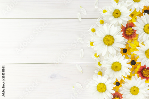 White daisies and garden flowers on a white wooden table. The flowers are arranged side, empty space left on the other side.