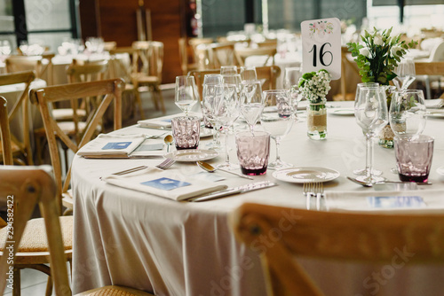 Tables and wooden chairs arranged and decorated in a wedding hall of a hotel © Joaquin Corbalan